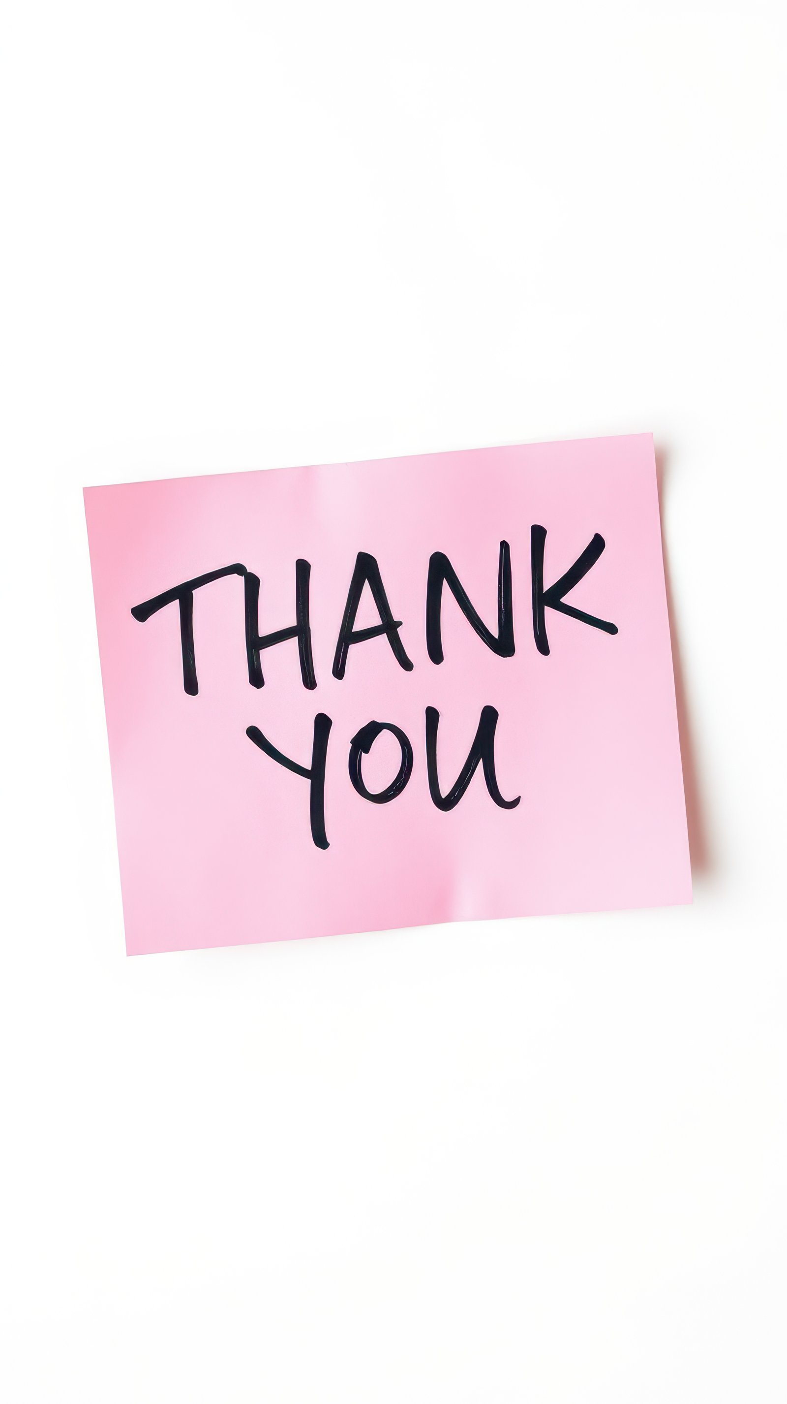 Simple thank you note on pink sticky paper placed against a white background conveying appreciation with a heartfelt message